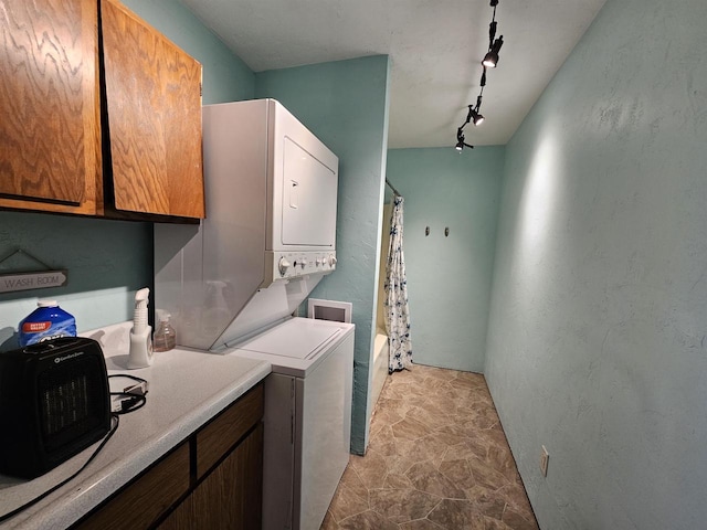 laundry area with track lighting and stacked washer / drying machine