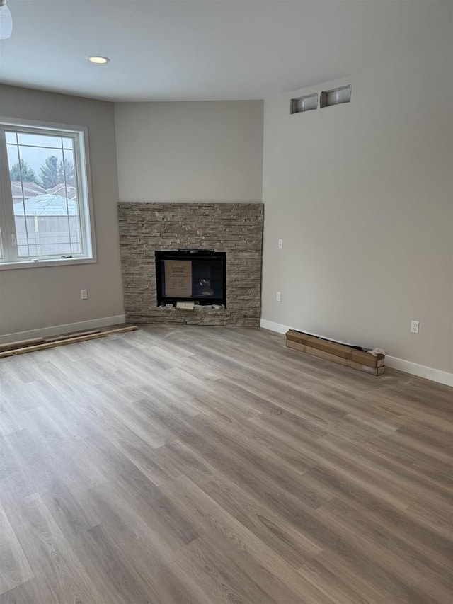 unfurnished living room with a stone fireplace and wood-type flooring