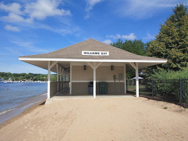 view of horse barn with a water view and a beach view