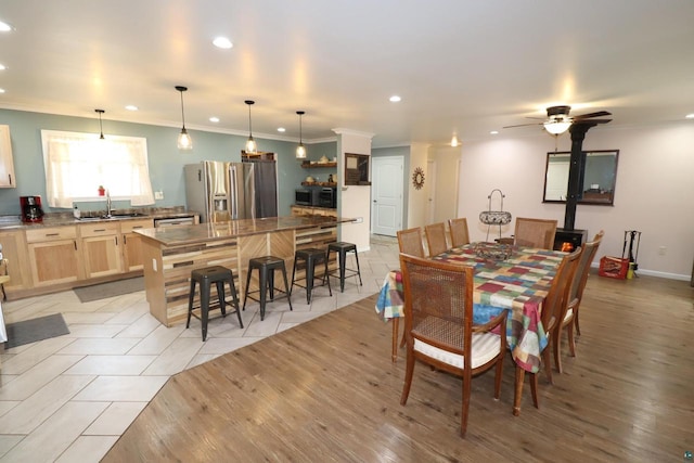 dining space featuring ceiling fan, sink, light hardwood / wood-style flooring, and ornamental molding