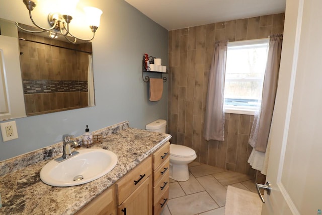 bathroom with tile flooring, large vanity, toilet, and a notable chandelier