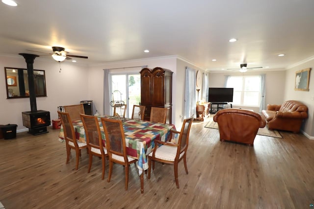 dining area featuring dark hardwood / wood-style flooring, ceiling fan, a wood stove, and crown molding