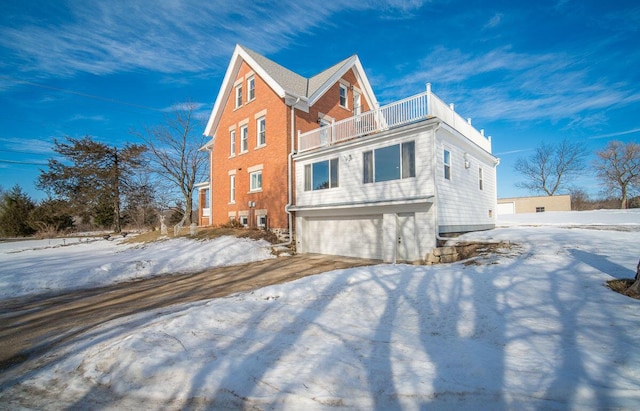 view of snowy exterior with a balcony and a garage