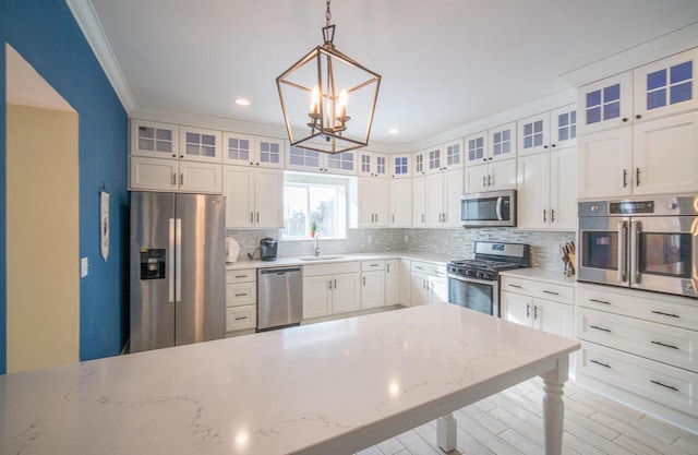 kitchen with white cabinets, hanging light fixtures, stainless steel appliances, and sink