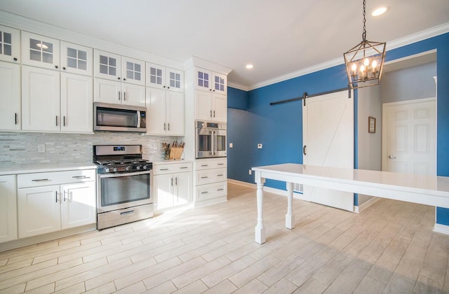 kitchen with a barn door, white cabinetry, tasteful backsplash, and appliances with stainless steel finishes