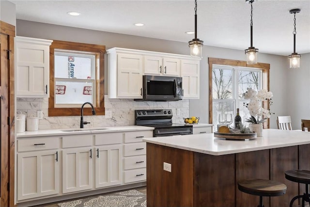 kitchen with hanging light fixtures, range with electric cooktop, sink, and white cabinets