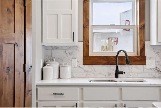 kitchen featuring tasteful backsplash, sink, and white cabinets