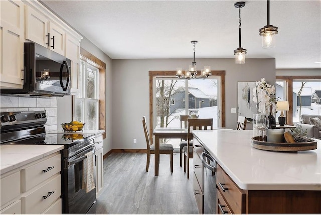 kitchen featuring hanging light fixtures, electric range, tasteful backsplash, a notable chandelier, and dark hardwood / wood-style flooring