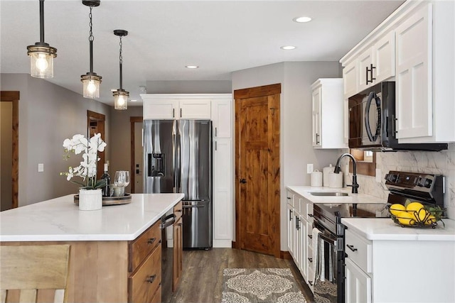 kitchen featuring decorative light fixtures, black appliances, white cabinets, and a kitchen island