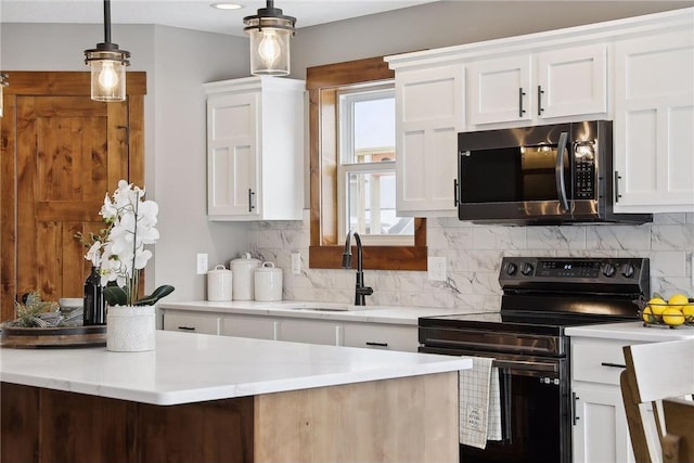 kitchen with pendant lighting, black electric range oven, sink, and white cabinets