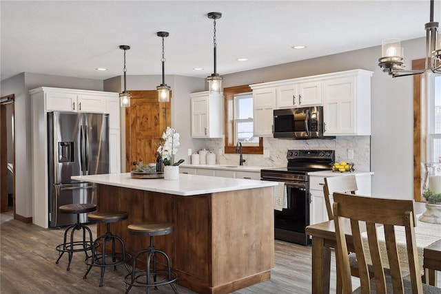 kitchen with a kitchen island, appliances with stainless steel finishes, pendant lighting, tasteful backsplash, and white cabinetry