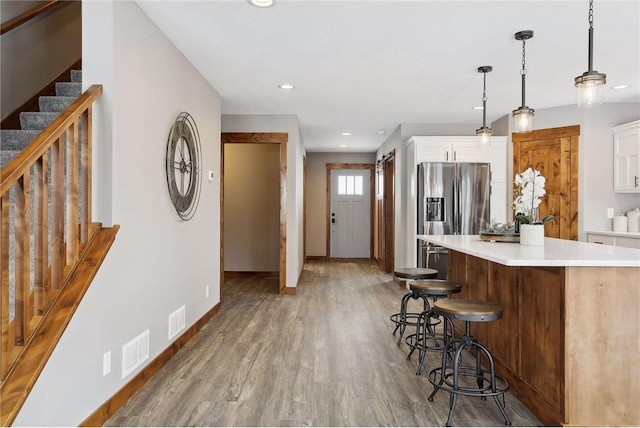 kitchen with a center island, hanging light fixtures, a kitchen breakfast bar, hardwood / wood-style floors, and white cabinets