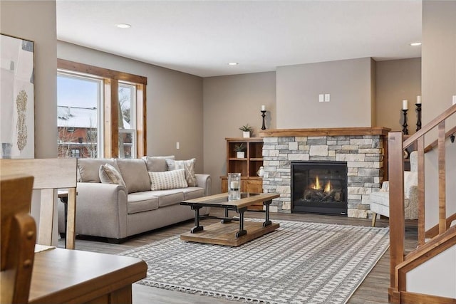 living room with a stone fireplace and light wood-type flooring