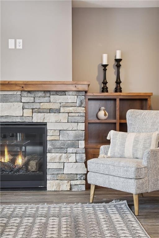 sitting room with a stone fireplace and hardwood / wood-style floors