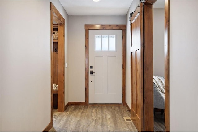 doorway featuring a barn door and light hardwood / wood-style flooring