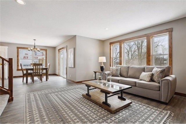 living room with an inviting chandelier, dark wood-type flooring, and a textured ceiling