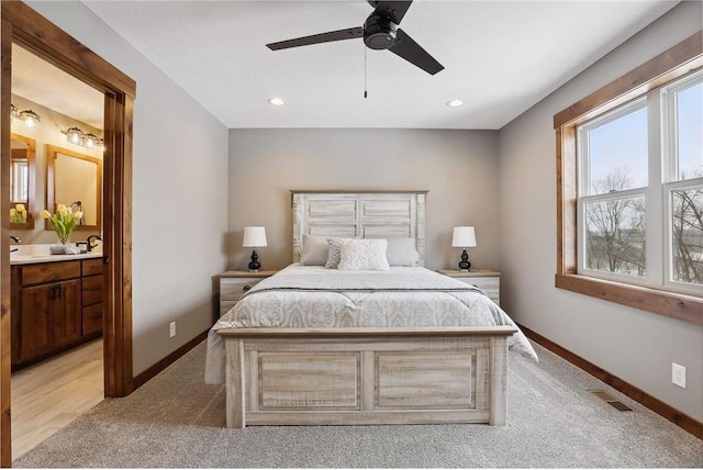 bedroom featuring ceiling fan, connected bathroom, and light carpet