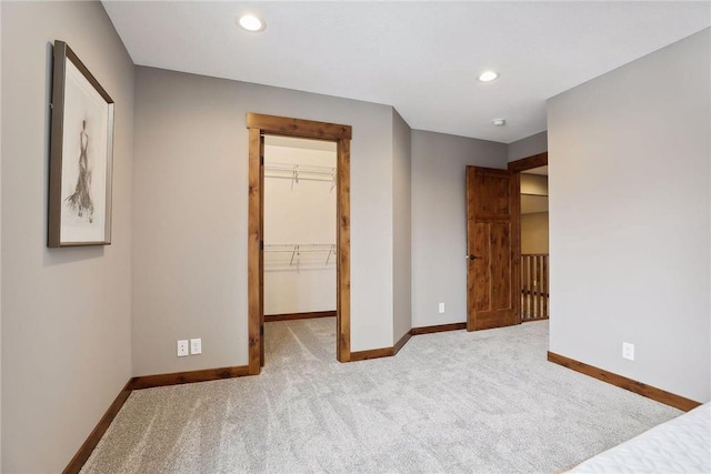 unfurnished bedroom with a spacious closet, light colored carpet, and a closet