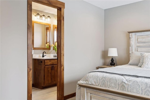 bedroom featuring sink, light hardwood / wood-style floors, and ensuite bath