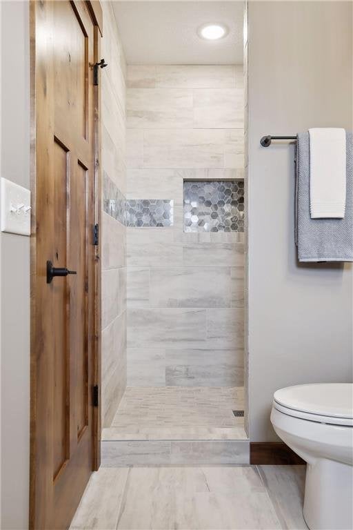 bathroom featuring toilet and a tile shower