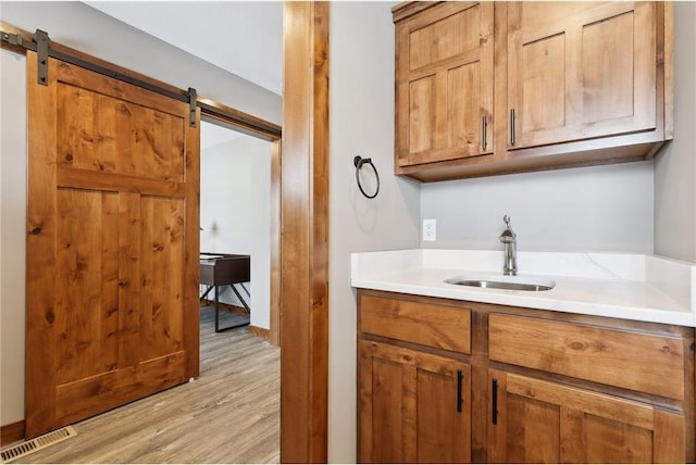 interior space with a barn door, sink, and light hardwood / wood-style floors