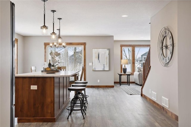 kitchen featuring hanging light fixtures, stainless steel fridge, dark hardwood / wood-style floors, and a kitchen bar