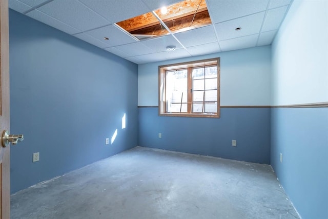 empty room with a paneled ceiling and concrete floors