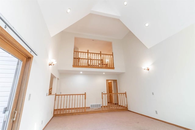 stairs with high vaulted ceiling and light carpet