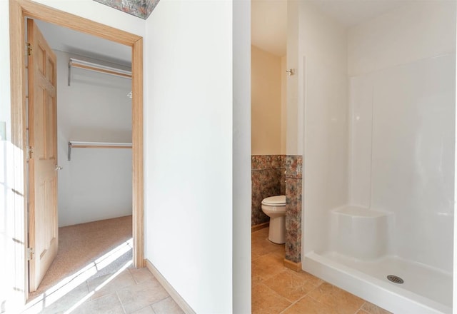 bathroom with a shower, tile flooring, and toilet