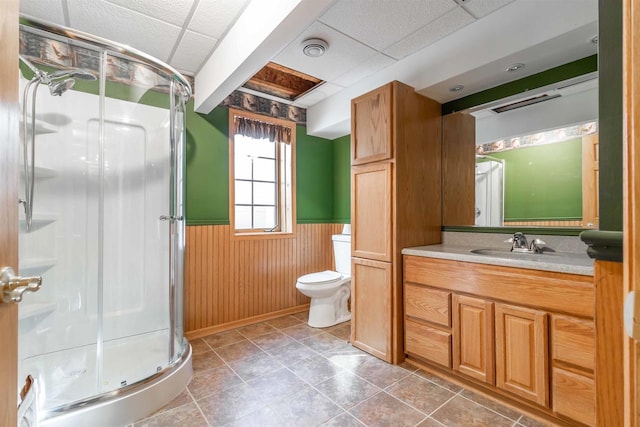 bathroom with walk in shower, tile floors, a paneled ceiling, toilet, and vanity