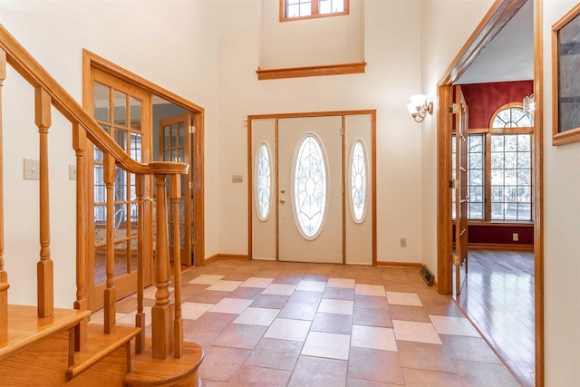 foyer with light tile floors, french doors, a healthy amount of sunlight, and a high ceiling