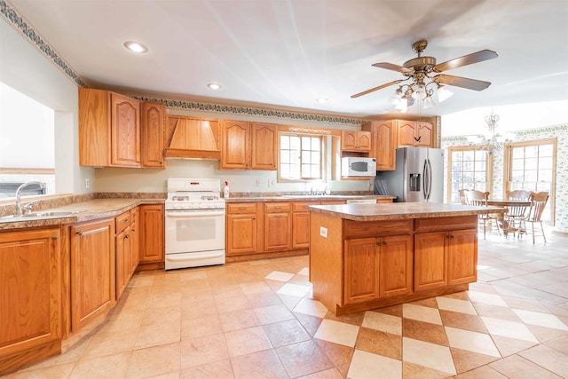 kitchen featuring white appliances, sink, light tile floors, premium range hood, and ceiling fan with notable chandelier