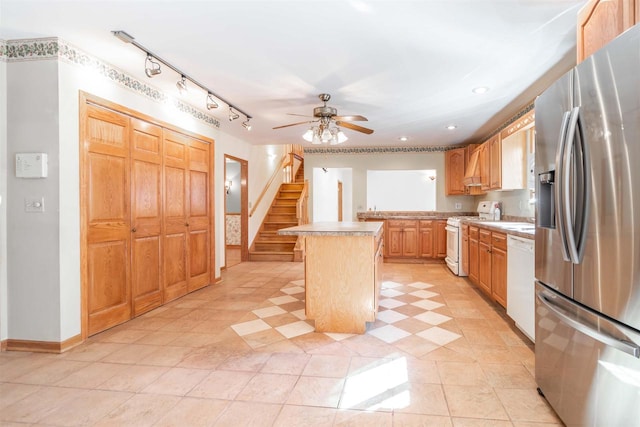 kitchen with track lighting, a center island, ceiling fan, white appliances, and light tile floors