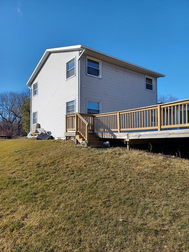 back of property with a wooden deck and a lawn