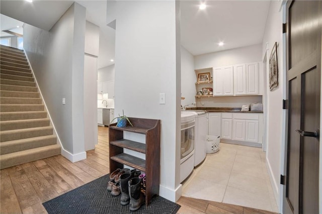 clothes washing area with cabinets, washer and dryer, and light wood-type flooring