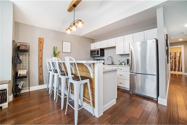 kitchen featuring hanging light fixtures, white cabinets, a breakfast bar, stainless steel appliances, and dark wood-type flooring