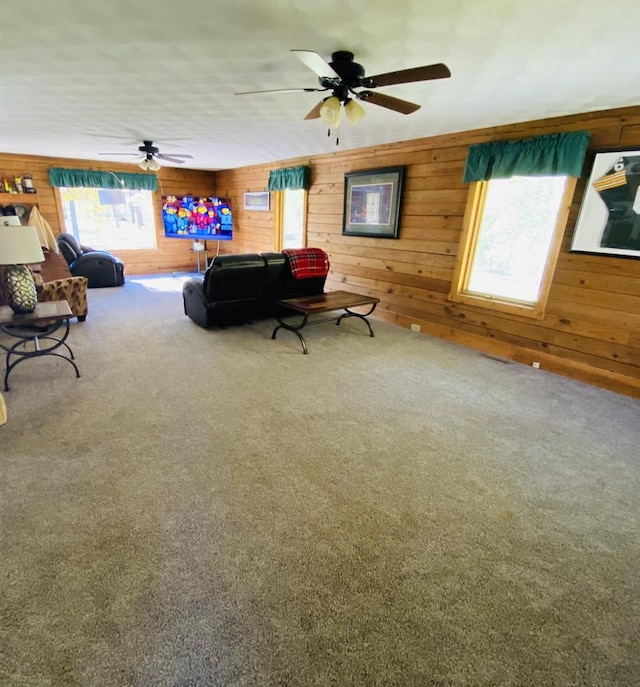 living room featuring ceiling fan, wooden walls, and carpet floors