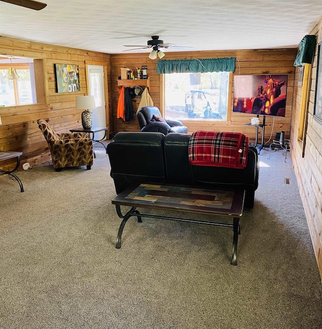 carpeted living room featuring wood walls and ceiling fan