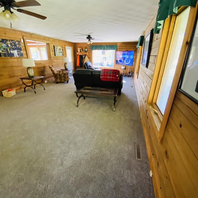 game room with ceiling fan, wooden walls, and carpet flooring