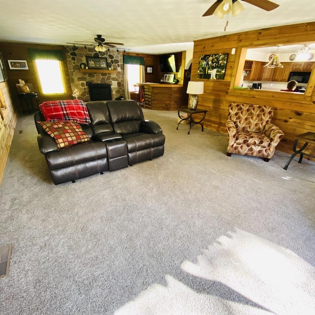 carpeted living room featuring a fireplace, ceiling fan, and wooden walls