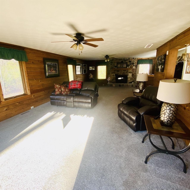 living room featuring plenty of natural light, carpet floors, a fireplace, and wooden walls