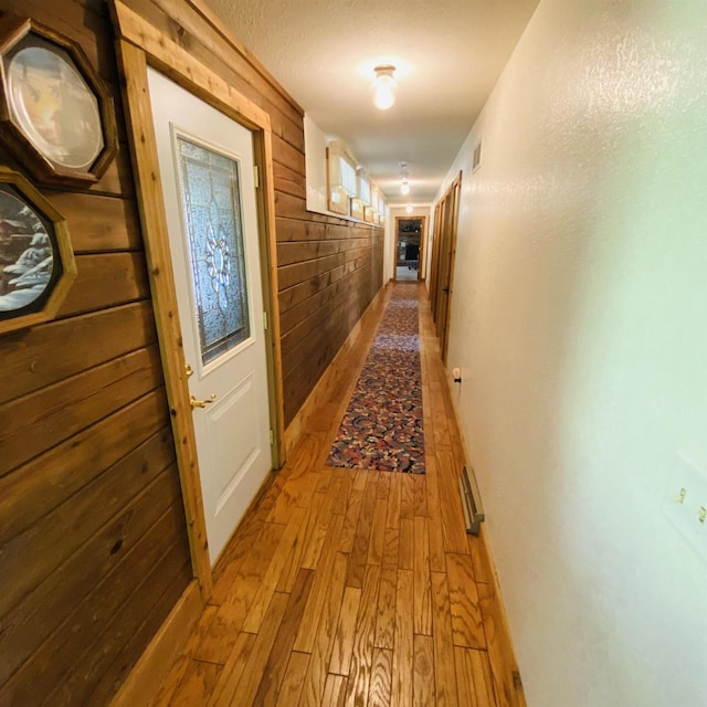 hallway featuring hardwood / wood-style flooring and wooden walls