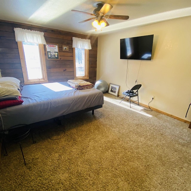 bedroom featuring wood walls, ceiling fan, and carpet flooring