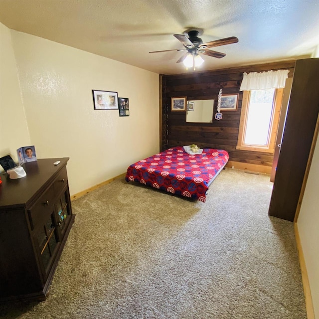 carpeted bedroom featuring ceiling fan, wood walls, and a textured ceiling