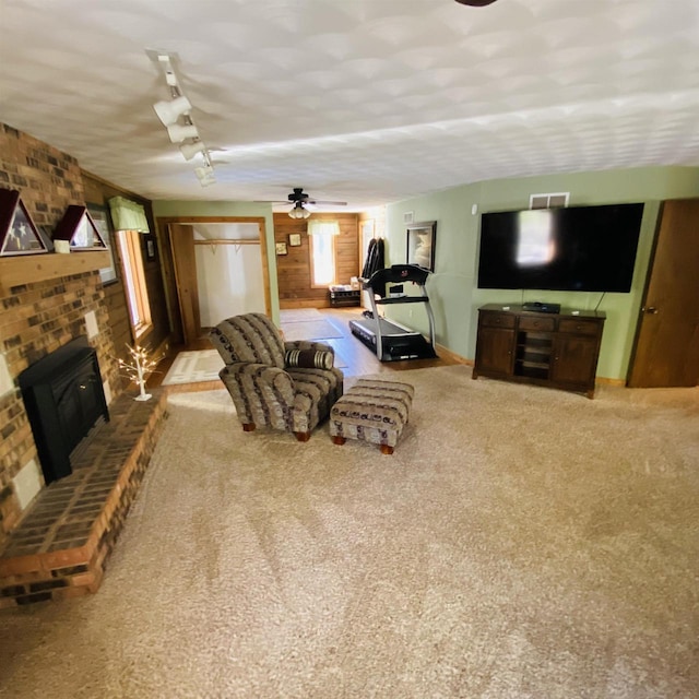 carpeted living room featuring ceiling fan, track lighting, and a fireplace