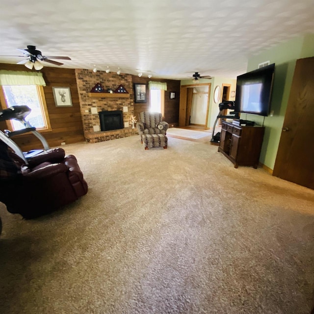 living room with carpet, ceiling fan, a textured ceiling, and a fireplace