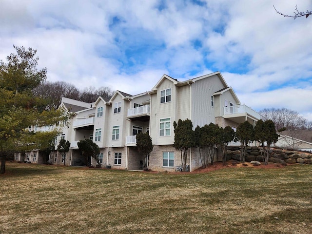 back of property with a balcony and a lawn