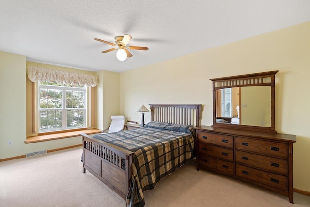 bedroom with light colored carpet, ceiling fan, and a textured ceiling