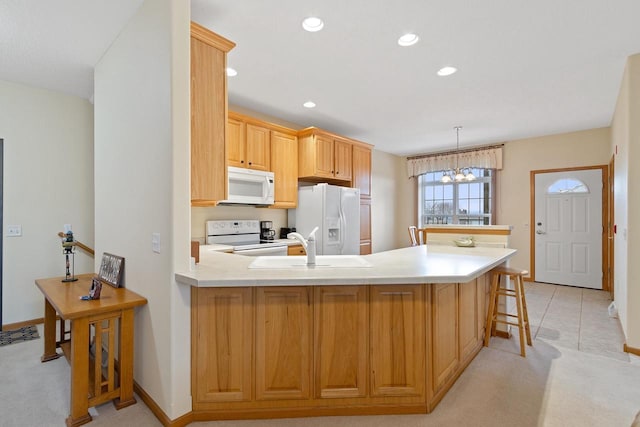 kitchen with a chandelier, white appliances, light carpet, hanging light fixtures, and sink