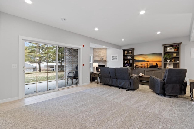 carpeted living room with a stone fireplace